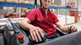 Сотрудник кладёт руку на многофункциональный рычаг управления от Linde Material Handling
